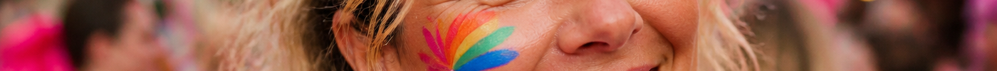 Vrouw met regenboog splitcake-schmink op de wang, festivalsetting